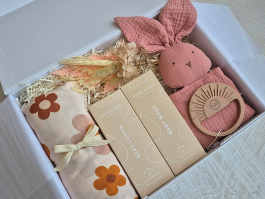 Baby girl gift hamper with retro flower swaddle, bunny comforter and other baby essentials. 